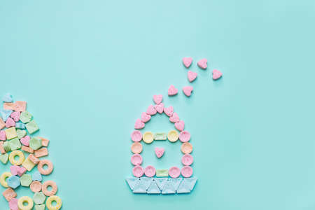 Sweet home made of candy with hearts on soft blue background. Congratulations birthday of newborn...