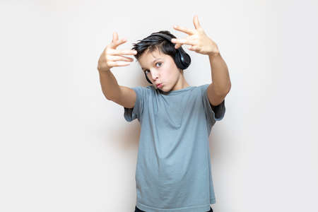 Photo of Young happy caucasian teenage school boy wearing headphones listening to music and moving...