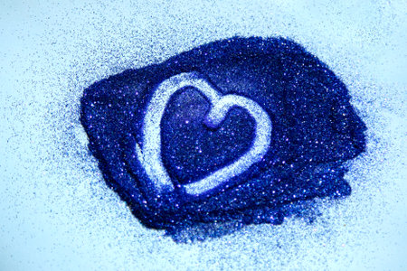 Blue glitter shaped as a heart on blue background. Symbol of love, Valentines Day. Close-up photoの写真素材
