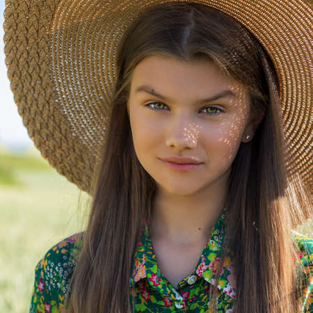 Young woman in straw hat on field in summer. Close up photoの写真素材
