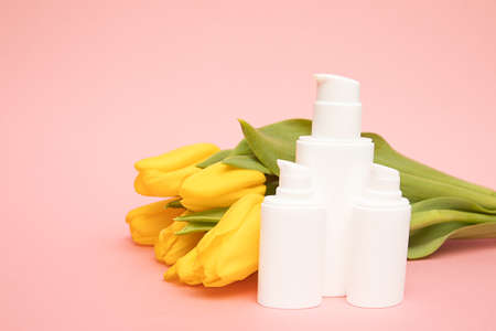 Yellow tulips on pink background with cosmetic bottles containers. Mock up. Happy mothers day,...