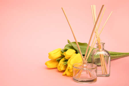 Air freshener with wooden aroma sticks and tulip flowers on pink background with copy space. Concept of fresh air at homeの写真素材