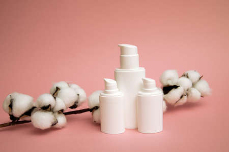 White container for cosmetic plastic bottle with cotton flower, blank label for mock up branding, Natural Beauty product concept. Pink backgroundの写真素材