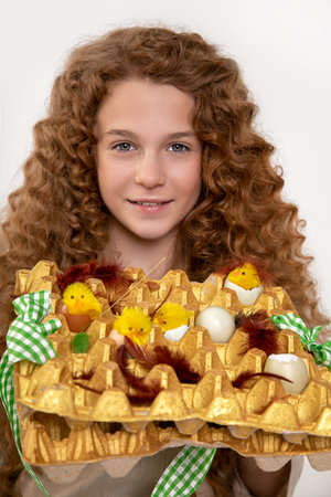 beautiful red-haired teenager girl with curly afro curls holding homemade Easter basket with toy...
