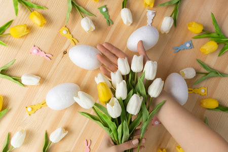Females hands holding bouquet of fresh tulip flowers on wooden pink background, flat lay composition...