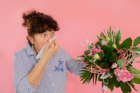 woman bouquet flowers hands take hankie sneezes closed eyes concept allergy illness discomfort pink backgroundの写真素材
