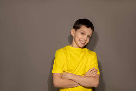 Portrait of teenage boy on gray background, arms crossed, toothy smile on gray backgroundの写真素材