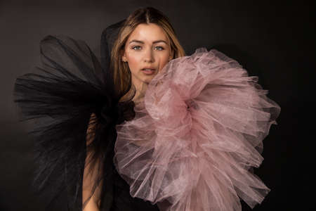 Studio photo of beautiful young woman wearing makeup and mesh evening dress while posing against black background, copy space, beauty concept for advertising parfume, looking through textileの写真素材