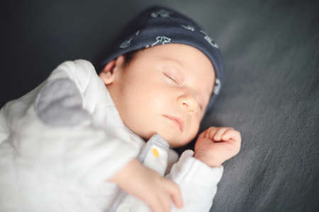 Photo of newborn baby sleeping on gray bedspread on bed. Happy motherhood concept, adoptionの写真素材