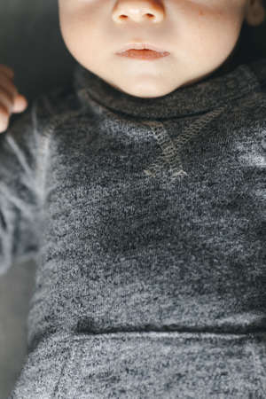 Cropped photo of newborn baby sleeping on gray background in gray bodysuit, copy space for your text or mock upの写真素材