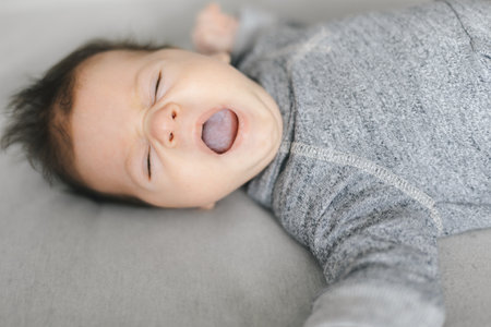 Newborn baby, yawning or talking on gray textile background. Copy spaceの写真素材