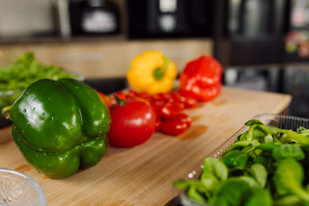 Foreground. Wooden cutting board, lies green pepper. Fresh ingredients for salad. healthy and proper nutrition concept. vegetarian food lifestyleの写真素材