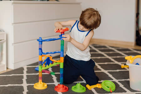 3 year old child is playing on floor at home. He designs and is totally focused on gameの写真素材