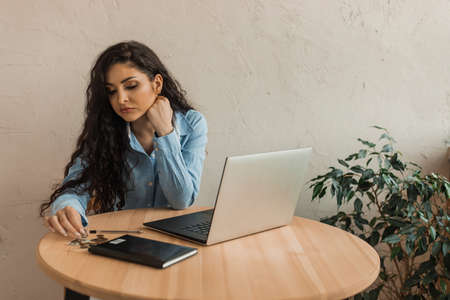Accountant woman 30 years old lost her job, is counting savings and is looking for a new job online.