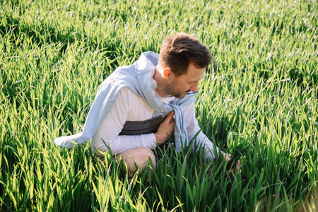 Young farmer with folder under his arm sitting in field 40 years old checking his forage crop, small bussiness concept photoの写真素材