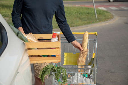 Man unloads food from cart intocar.Eco-friendly use of packaging. Close-up photo.の写真素材