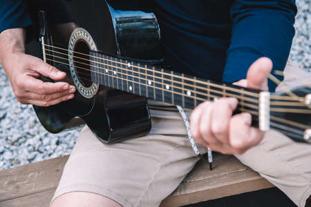 Young man learns to play guitar on streets of city. Lifestyle. High quality photo