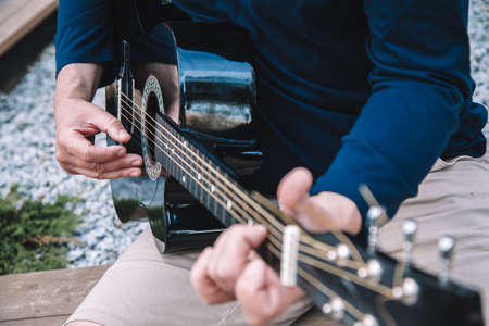 Man learns to play guitar on streets of city. Lifestyle. Close-up photoの写真素材