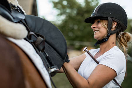 Happy woman in sports helmet communicates with her horse before training. Sports and health. Concept of proper lifestyle. Role model.Close-upの写真素材