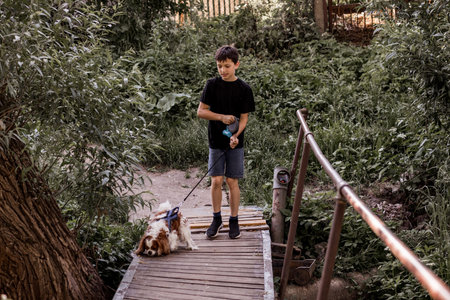 Teenage boy walks with dog on bridge in the countryside