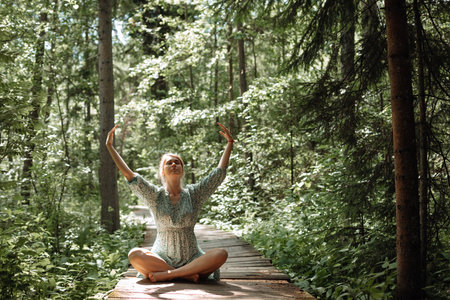 Woman doing breathing exercises in woods in fresh air. Concept of healthy lifestyle, solitude and merging with nature. High quality photoの写真素材