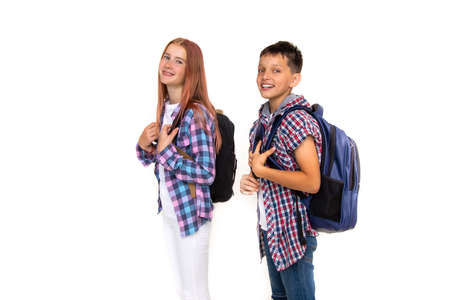 Boy and girl teenager 11 years old schoolboy and schoolgirl looking at camera on white background with backpacks and smiling. Dressed in plaid shirt, white shirtの写真素材
