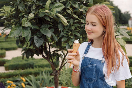 teenager girl in denim dress eating Ice-creamin hot summer day, photoの写真素材