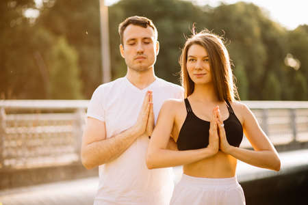 Young couple man and woman meditate together outdoorsの写真素材
