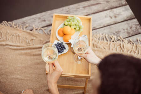 Top view of young happy unrecognizable couple on romantic picnic near river or lake, woman and man drinking wine outdoors together, people having fun on vacation, love emotionの写真素材