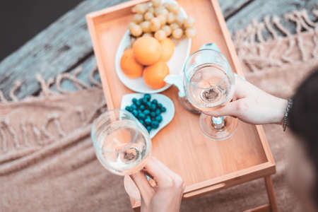 Top view of young happy unrecognizable couple on romantic picnic near river or lake, woman and man drinking wine outdoors together, people having fun on vacation, loveの写真素材