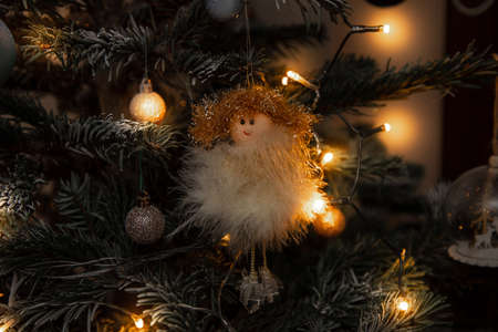 Toy handmade decoration, small fluffy angel hangs on the green branch tree on eve against Merry Christmas lights. Happy New Year conceptの写真素材