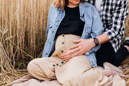 Man gently hugs his pregnant wife's stomach with his hand, listening to movements of child. Pregnancy and care. Happiness and tenderness. Care and attention. Love and attention.Family values.の写真素材