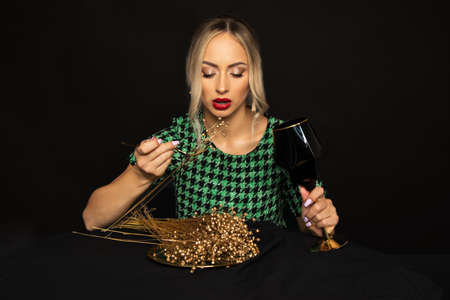 Bridal gold diet for Luxurious young blonde woman in green dress on black background is bored on diet. Eating Disorder Concept. Studio shot.の写真素材