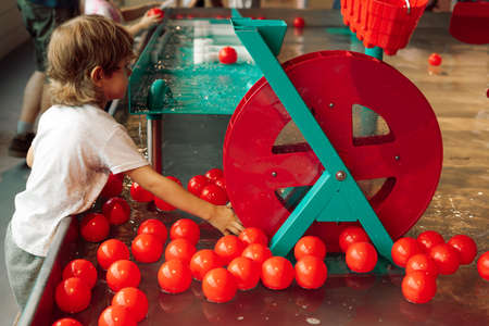 Bright water equipment and balls completely captured attention ofboy in children's entertainment center. Children's entertainment center. Tactile sensations. Educational classes and games.の写真素材