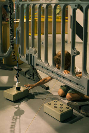 Little boy reaches out with his hand to part of mechanism in children's entertainment and game center. Modern technologies. Control and security. Training and development. Super game.の写真素材