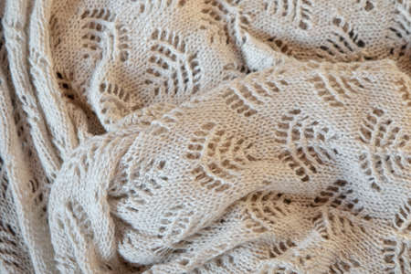 Knitted handmade blanket scarf plaid with patterns in beige, close-up photo, full frame, top view. Great background of natural wool, cotton. Lifestyleの写真素材