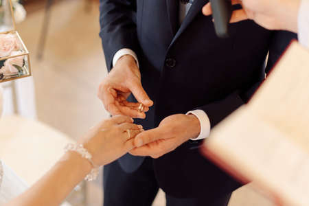 Man puts engagement ring on finger of his beloved during wedding ceremony. Concept of merging and creating family, wedding rings are symbol of love. High quality photoの写真素材
