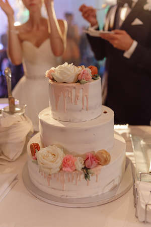 Wedding cake newlyweds at celebration, decorated with sweet roses. small business concept, baking cakes and sweets for events. unrecognizable people. High quality photoの写真素材