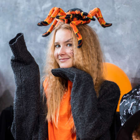 Teenage girl among decor for Halloween holiday, huge spider on her head. Close up photo, orange blakc colorsの写真素材