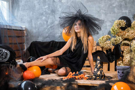 Teenage girl in hat among decor for Halloween holidayの写真素材