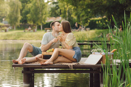 Couple in love is kissing on picnic on summer day in beautiful place on wooden pier. Happiness and serenity. Rest and enjoyment .Beautiful moments of life. Super day. Romantic relationships.の写真素材