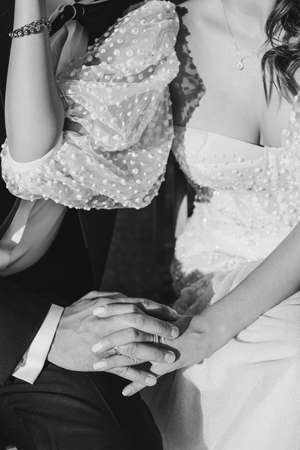 Black and white crop photo of bride and groom's hands in wedding dress. Unrecognizable persons.の写真素材