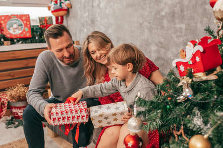 Photo of Dad, mom and son. Spending time. Christmas tree at home has happy moments. Preparing for holiday. Family with one child. Happiness. Have fun. Simple livingの写真素材