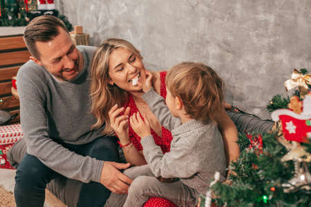 Dad, mom and son. Spending time. Christmas tree at home has happy moments. Preparing for holiday....