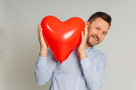 An unidentifiable man hid behind inflatable balloon shaped red heart. concept of declaration of love...