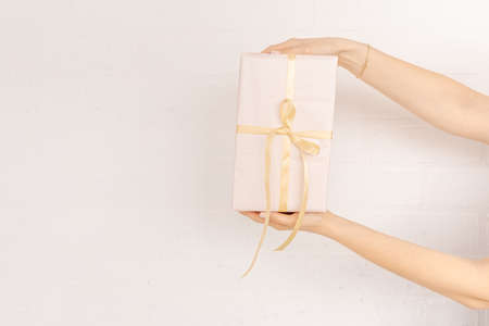 Female hands hold on white background.Gift box wrapped in paper. Gift wrapping tape. Gift concept...