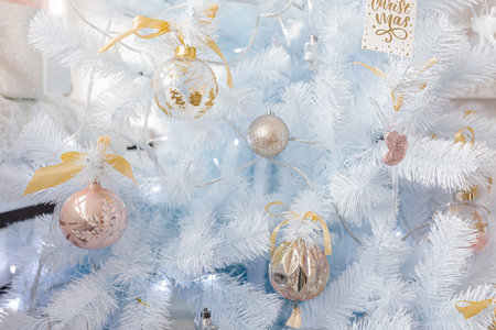 White Christmas tree decorated with silver golden pink Christmas balls and beautiful glass balls on...