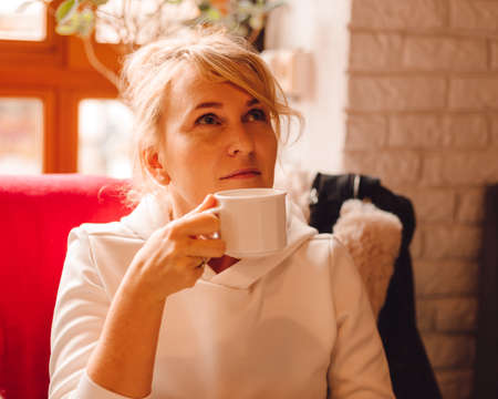 Photo of Dreaming cute young woman drinking coffee, Beautiful curly hair woman sitting in cafe and enjoyingh coffee in hand in cup.の写真素材