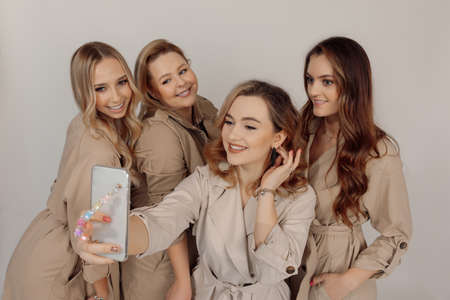 Photo of Four cute young positive woman having fun. Beige trench coat. Laughing. Smiling. Fun moment...