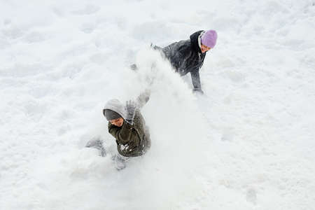 Boy and girl, teenagers, brother, Sister indulge, roll around in snow on snowy day In winter,...